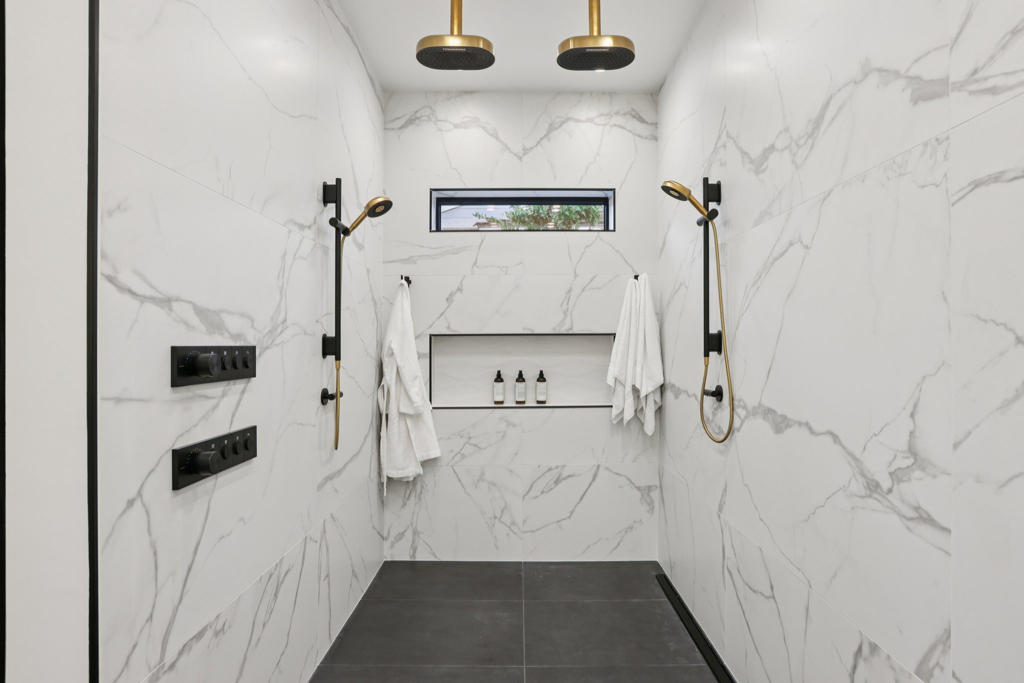 Primary shower with two ceiling-mounted rain showerheads and two hand showers