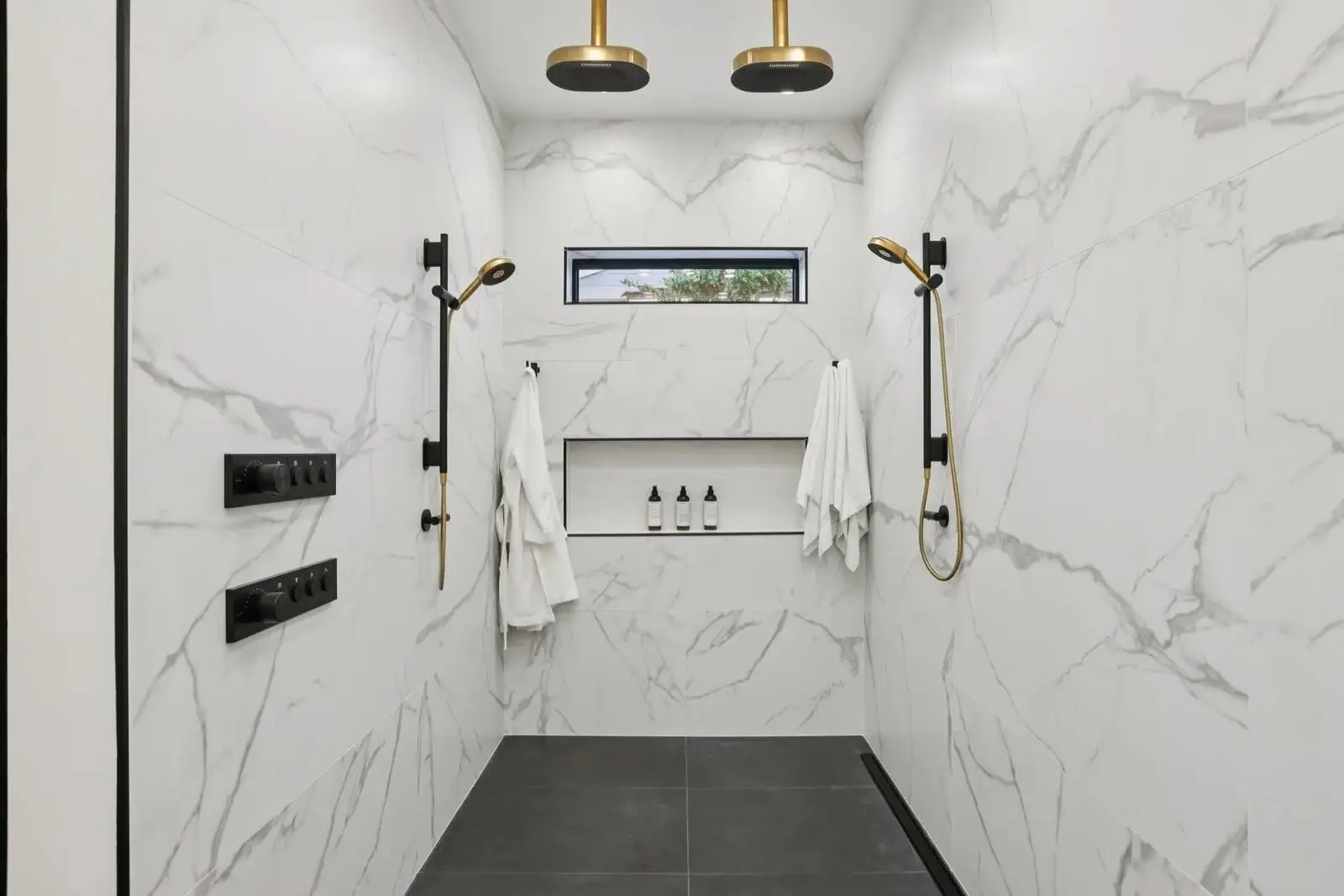 Primary shower with two ceiling-mounted rain showerheads and two hand showers